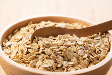 Oatmeal and wooden spoon set against a wooden background
