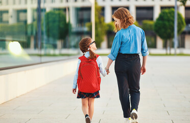 first day at school. mother leads  little child girl in grade.