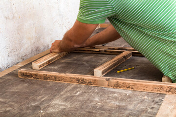 Male carpenter working on old wood in a retro vintage workshop.