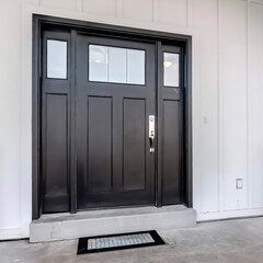 Square frame Home entrance with front porch and black front door against white panelled wall