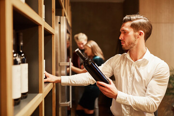 Junger Mann als Sommelier mit einer Flasche Wein
