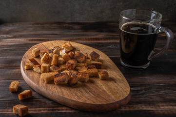 Homemade tradishional russian kvass in cup and rusk on cutting board on wooden background. Wonderful healthy refreshing drink for summer