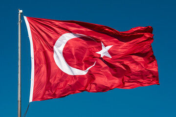 Turkish flag waving in blue sky.