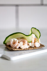 shrimp and cucumber open sandwich on marble background with copy space