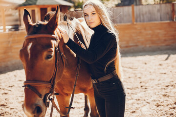 Fototapeta premium Girl with a horse. Woman in a ranch. Blonde in a black sweater
