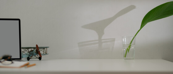 Obraz premium Copy space on minimal worktable with blank screen laptop, schedule book, decoration, and plant in a glass vase
