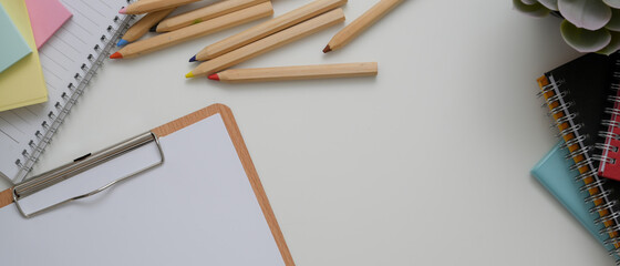 White office desk with paper on clipboard, stationery, other office supplies and copy space