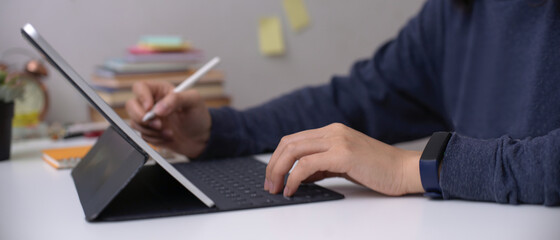 Female employee working on digital tablet with stylus pen on office desk