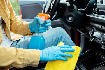 Fototapeta premium partial view of man in latex gloves using antiseptic spray and rag for cleaning car interior during covid-19 pandemic