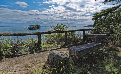 Empty stone bench in a park looking out over a bay with a small island visible