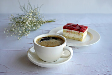 white coffee mug on a white background with dessert on a white plate, flowers in the background