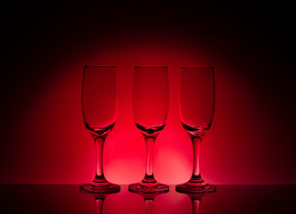 empty wine glasses in a row, with a graduated red background
