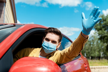Naklejka premium man in medical mask and protective gloves waving and driving taxi during covid-19 pandemic