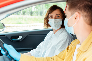 Fototapeta na wymiar man and woman in medical masks and protection gloves sitting in car during covid-19 pandemic