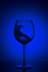 Splash of water in wine glass on blue background