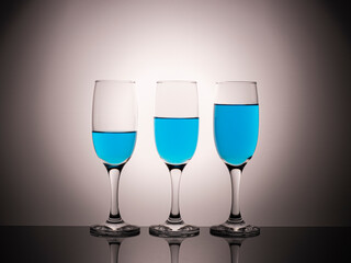 glass glasses with blue wine on a beautiful gradient background