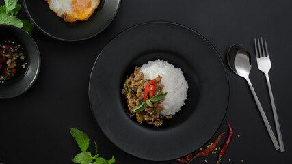 Stir fried minced pork with basil (Pad ka prao), rice, fried egg and chili fish sauce on black dinning table