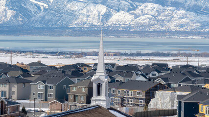 Panorama Church spire against neighborhood homes with snowy mountain and scenic lake view