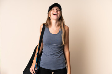 Young sport Lithuanian woman holding a sport bag isolated on beige background laughing