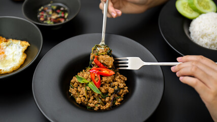 Female eating Thai traditional food, Stir fried minced pork with basil (Pad ka prao), fried egg and chili fish sauce
