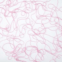 Pink woolen yarn, loose thread lies carelessly on a white background, for design, mock-up