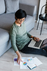 Image of asian man working with laptop and documents while sitting