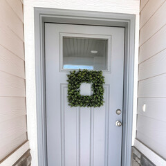 Square Square leafy wreath on front door entrance with glass pane and transom window