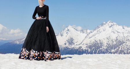 A beautiful young girl is standing in the snowy mountains in the spring, sunny weather in a...