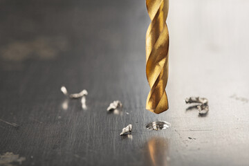 metal drill bit make holes in steel billet on industrial drilling machine with shavings. Metal work...