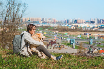 Fototapeta premium A happy Girl and a Labrador Retriever hug and smile while sitting on a mountain. Walking with a dog in the city.