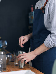 A man cook in a blue apron is cooking in the kitchen, the process of preparing a cocktail