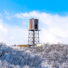 Obraz premium Square Water tank storage container on a tower at the snowy slope of Wasatch Mountains