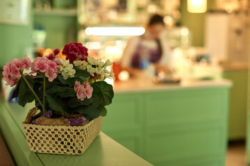 basket with flowers and blur woman working in confectionery shop. sweet store