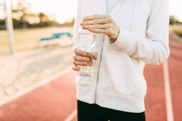 Athletic girl holds a water bottle while standing outdoors in a stadium