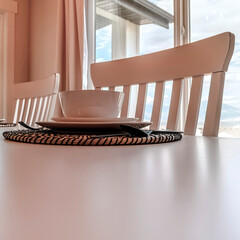 Square crop Tableware and utensils on woven placemat at the dining table with chairs