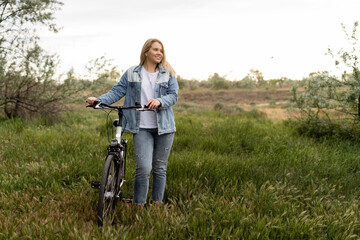 active lifestyle, a young beautiful woman goes near a pleasure bike. Rest at nature. Ride in the park. Fresh air,