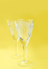 two crystal wine glasses on a yellow background