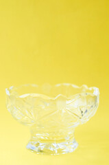 Empty crystal salad bowl on a yellow background close up