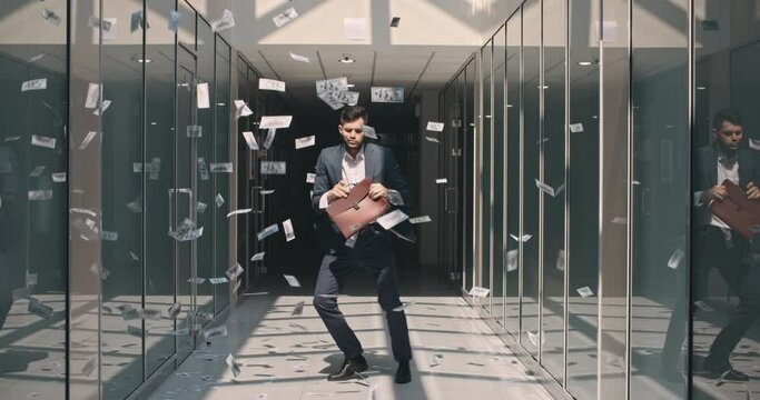 Lucky caucasian businessman is celebrating his victorious achievement by dancing in money rain in office hall - way to success concept 4k