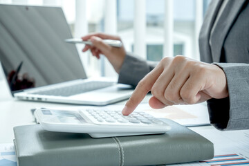 Business woman uses a calculator to calculate financial graphs that show results and analyze financial arrangements for business investment