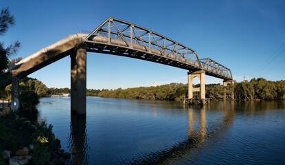 Panoramic view of pedestrian and water pipe bridge across a calm Parramatta river near Rydalmere, New South Wales, Australia