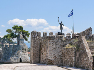 Estatua Héroe griego en el puerto de Lepanto, Grecia con la bandera griega al viento.