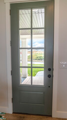 Vertical crop Front door with balck knob and glass panes against white wall and wood floor