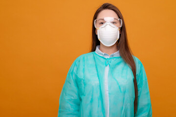 woman in protective equipment in medical mask on yellow background, coronavirus pandemic, look at the camera
