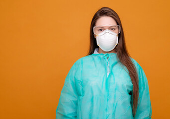 woman in protective equipment in medical mask on yellow background, coronavirus pandemic, look at the camera