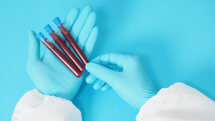 model with PPE cloth and Hand with glove is holding blood test tube on blue background.