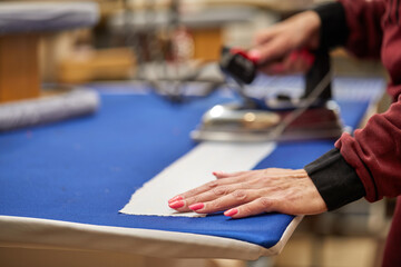 Tailor ironing the fabric. seamstress irons dress in a sewing workshop