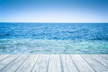 Obraz premium Wood table top over summer sea and blue sky with white clouds background. Montage style to dispaly the product