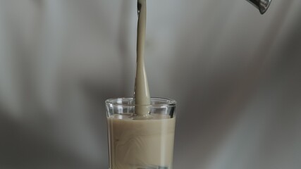 The bartender pours irish cream from jigger to cocktail glass with sambuca. Close up