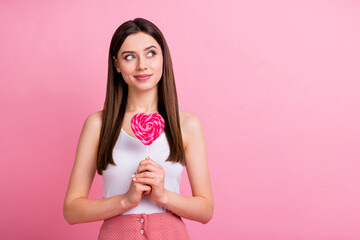 Close-up portrait of nice-looking attractive lovely charming cute pretty dreamy cheery straight-haired girl holding in hands lollipop counting calories isolated over pink pastel color background